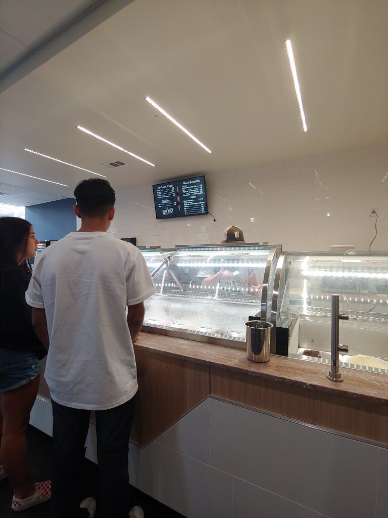 Shoppers in line at an accessible ice cream shop.