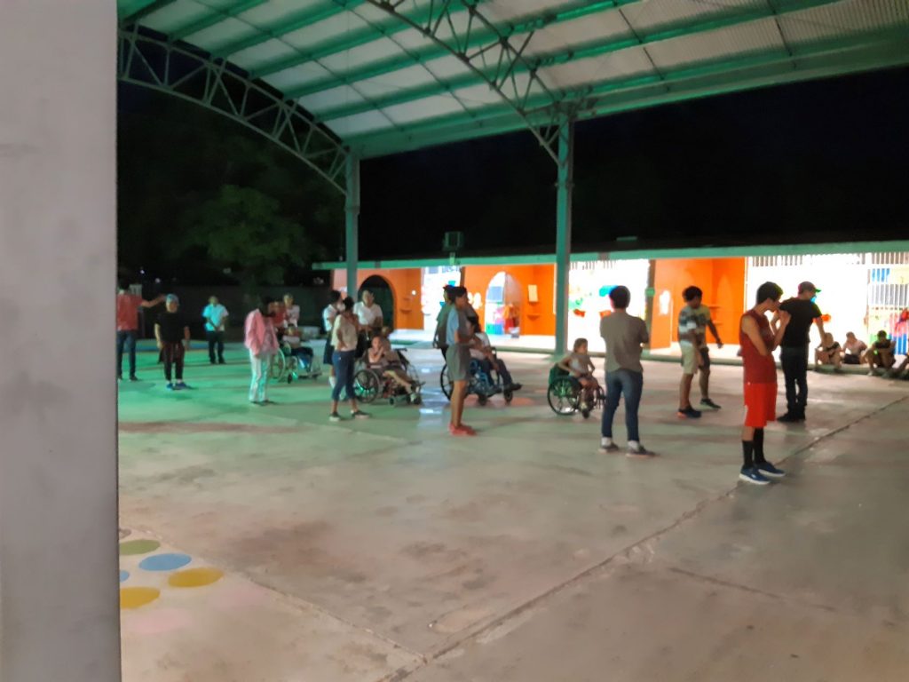 Group of dancers, including wheelchair users, practicing in the dark in a school playground in Cozumel Mexico.