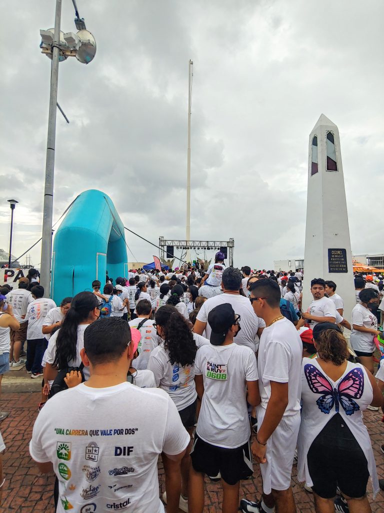 A large group of Cozumel residents wearing Paint and Run's white shirts stand close together as they wait for the race to begin.