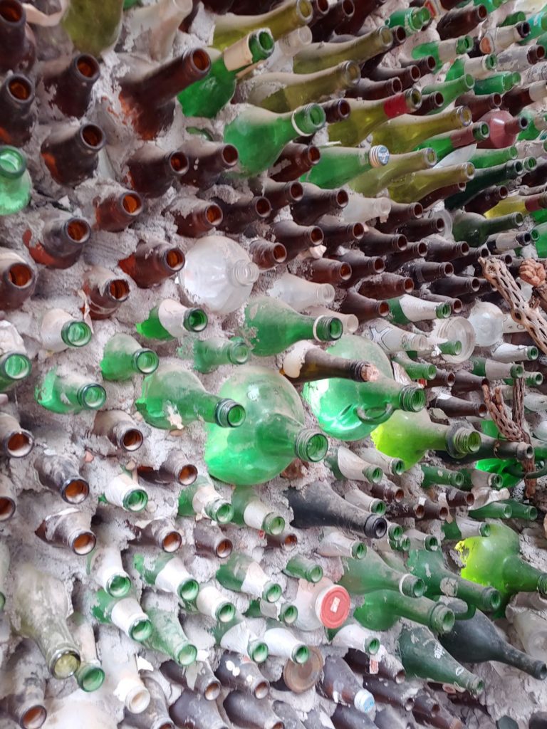 a wall built from stacked green and brown glass bottles cemented together in Tinker Town museum,, New Mexico.