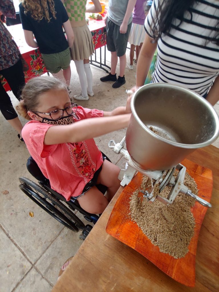 Girl in wheelchair learning to make tortillas during accessible Spanish lesson in Merida, Mexico.