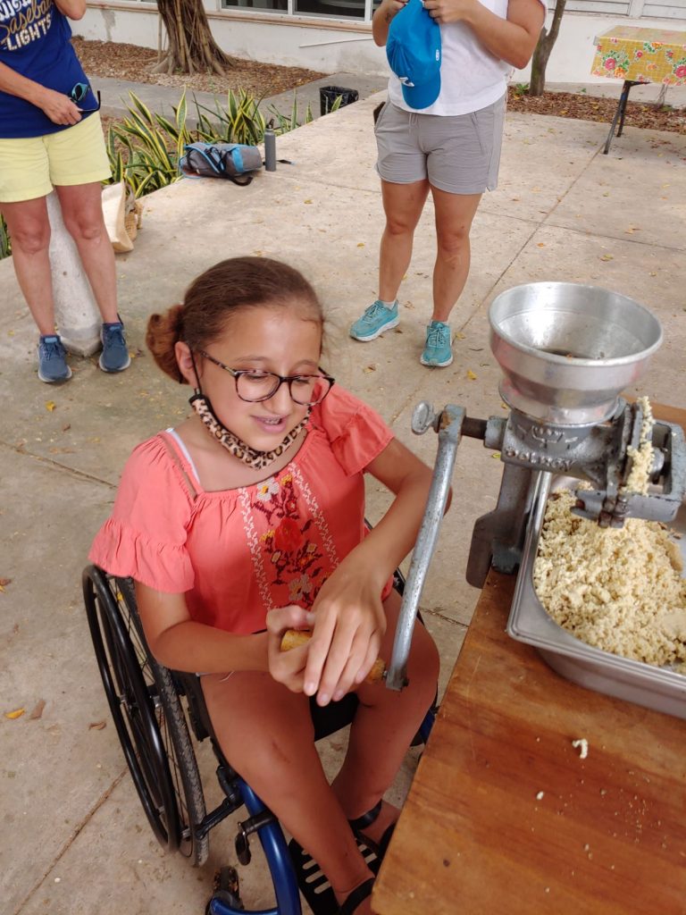 Girl in wheelchair learning to grind corn during accessible Spanish lesson in Merida, Mexico.