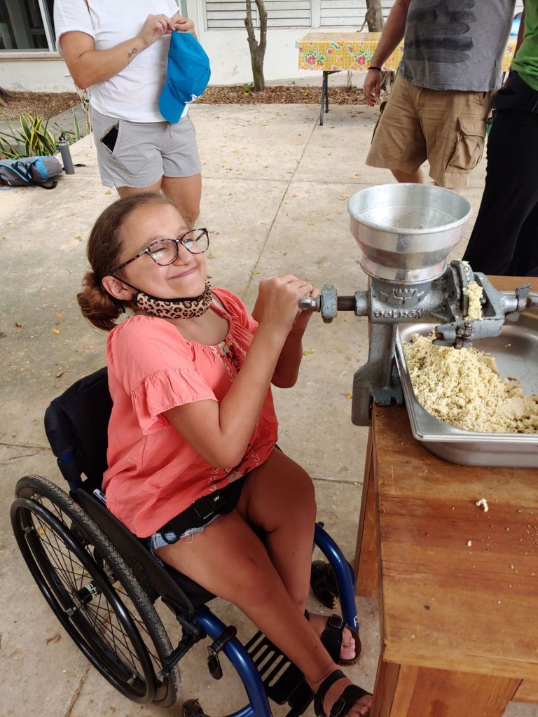 Girl in wheelchair learning to grind corn during accessible Spanish lesson in Merida, Mexico.