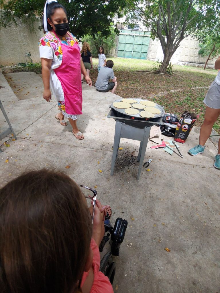 Girl in wheelchair learning to make tortillas during accessible Spanish lesson in Merida, Mexico.