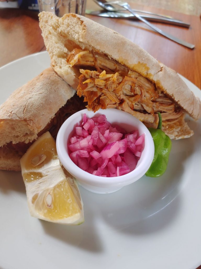 Pork sandwich served with bright pink pickled onion from accessible Yucatan restaurant, MUGY, in Merida.