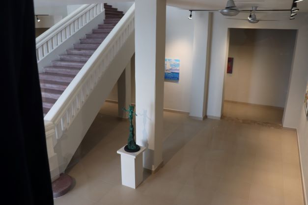 View of the first floor from above. Art is shown on the walls and a sculpture is on a white pedestal.