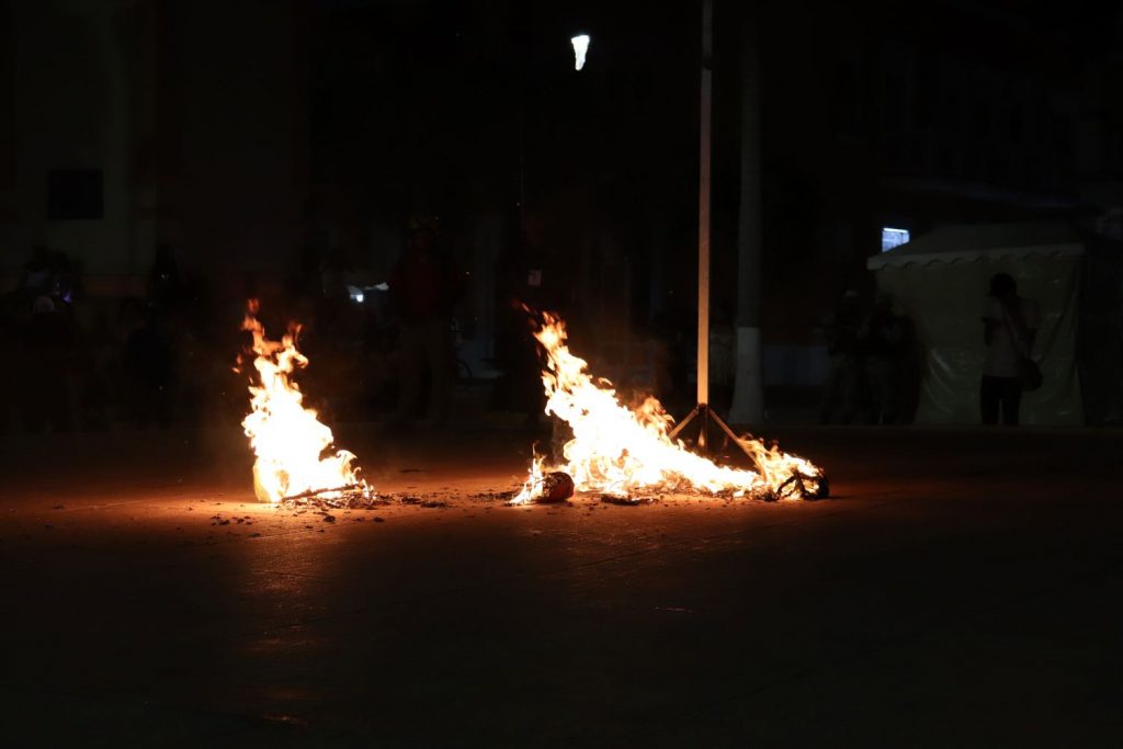 Bright flames against an otherwise dark night. The Juan Carnaval effigy has collapsed in pieces onto the stage floor and continues to burn in Cozumel Mexico.